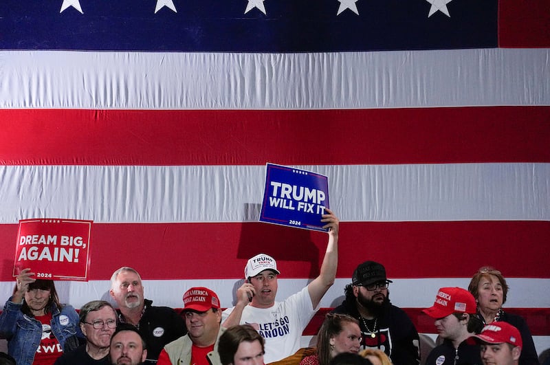 People hold signs ahead of Republican vice presidential nominee Sen. JD Vance speaking during a rally on Nov. 3, 2024, in Derry, New Hampshire.