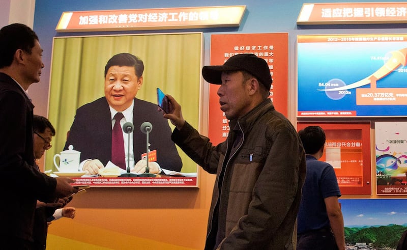 民众走过贴有习近平照片和中国经济增长情况的宣传海报(美联社)